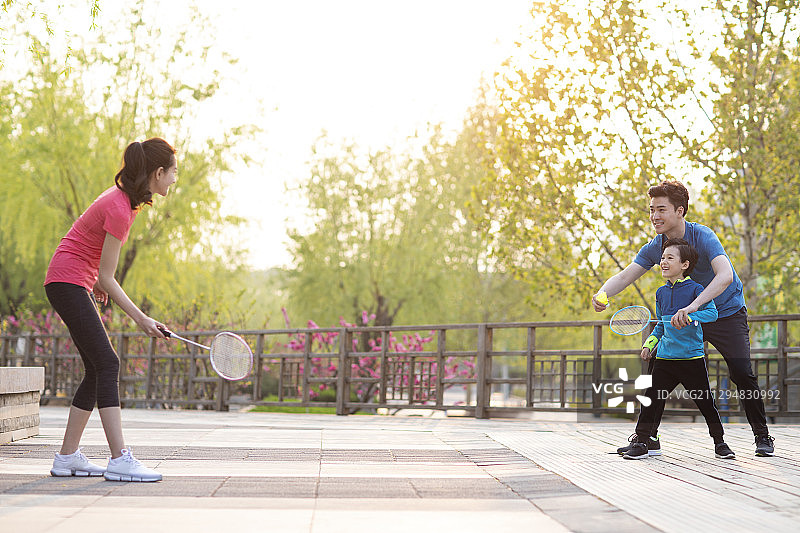 快乐的年轻家庭在公园打羽毛球图片素材