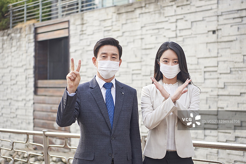 商人和妇女戴着污染口罩站在户外，手举2号和X号牌子图片素材