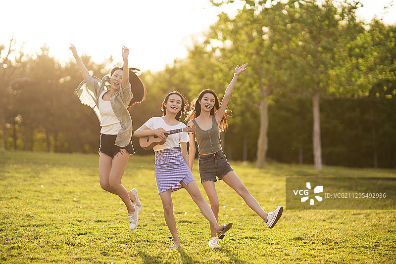 年轻闺蜜在草地上跳舞唱歌演奏音乐图片素材