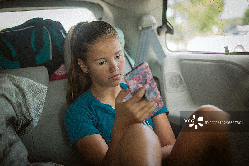 美国芝加哥，一名少女在汽车后座上使用手机图片素材