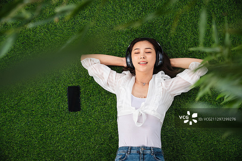 躺在草地上听音乐的青年女人图片素材