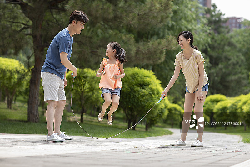 快乐的年轻家庭在公园跳绳图片素材