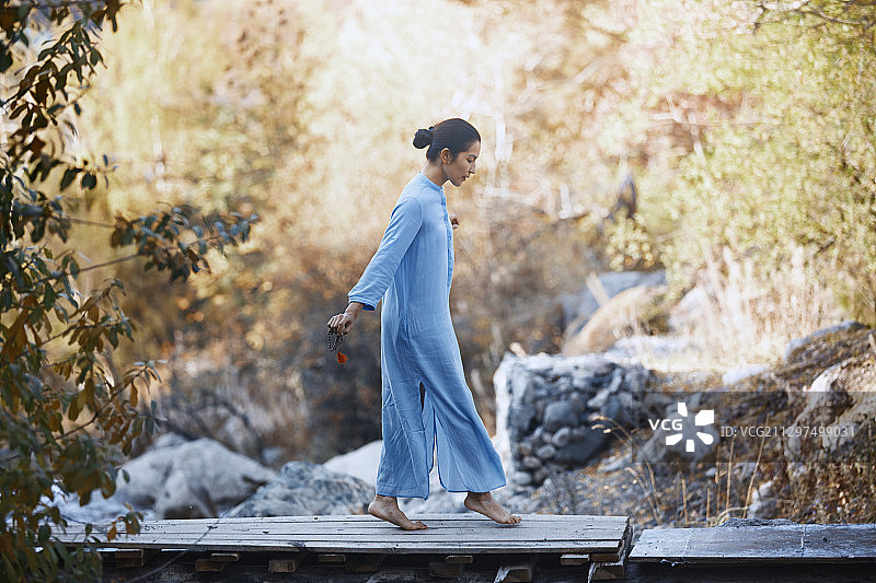 身穿传统佛教服饰的女子在桥上行走图片素材