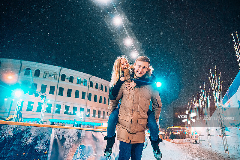 一对幸福的夫妇穿着暖和的衣服站在白雪覆盖的街道上图片素材