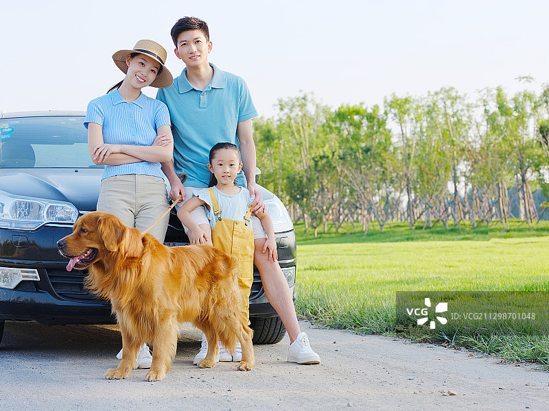 快乐的三口之家和宠物狗在停车场合影图片素材