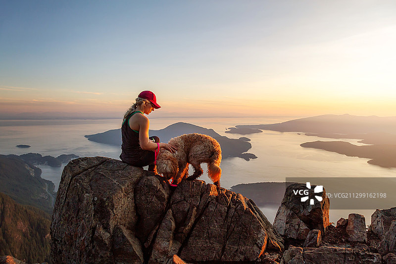 日落时分，女人和狗在岩石上图片素材