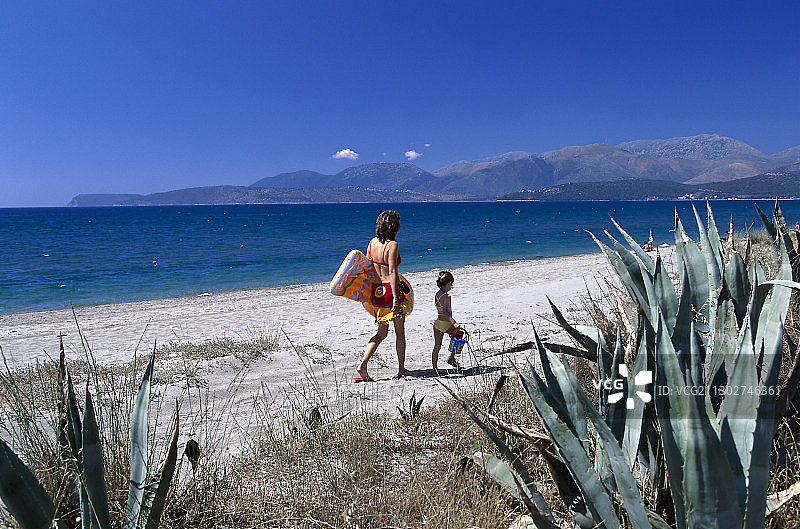 母亲和4-6岁的女儿在希腊伯罗奔尼撒半岛拉科尼亚吉西奥附近的海滩上散步图片素材