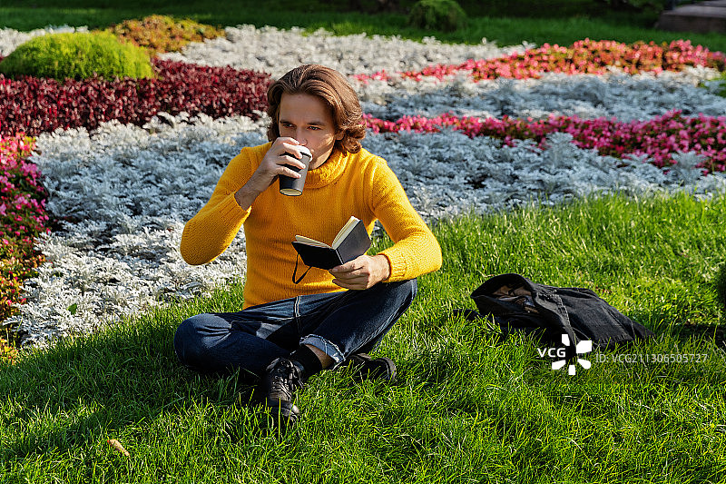 在公园里喝咖啡看书的男人图片素材