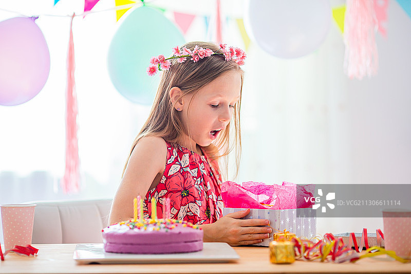 年轻女孩在生日聚会上打开生日礼物在家图片素材