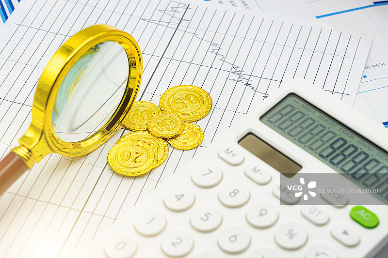 金融经济图表上的计算器、放大镜和硬币图片素材