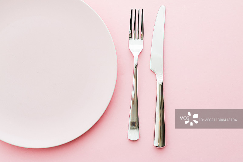 正上方拍摄的餐具和盘子的粉红色背景图片素材