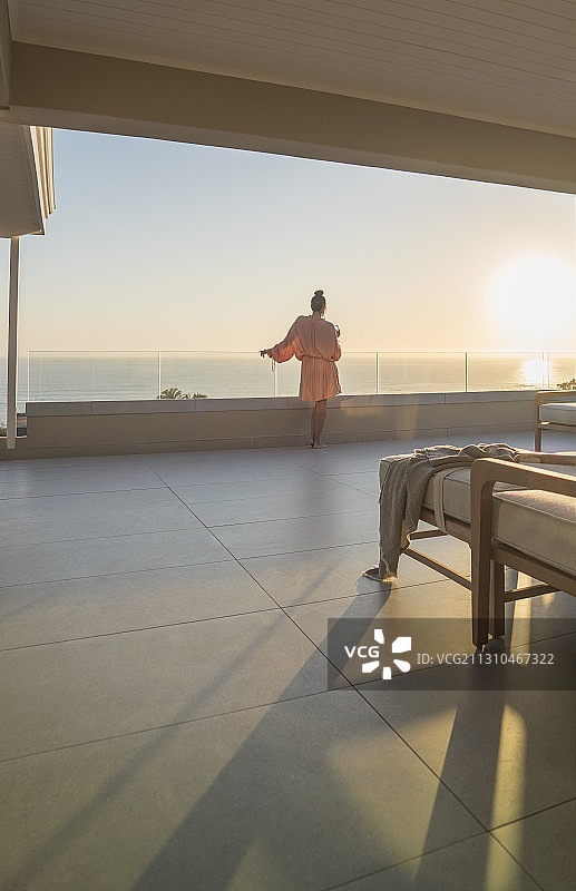 女人在浴衣享受海洋日落从豪华阳台图片素材