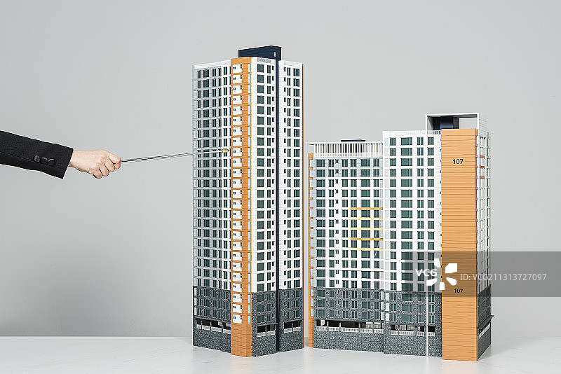 灰色背景下，用木棍指着公寓复杂模型图片素材