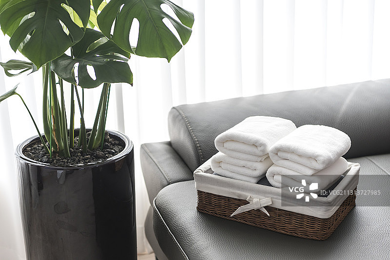 叠好的毛巾放在沙发上花盆和窗帘旁边的篮子里图片素材