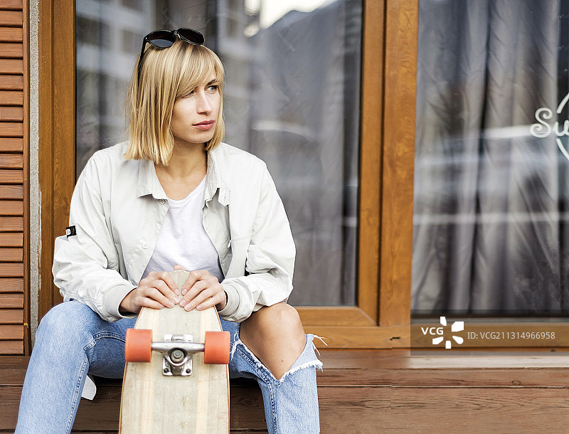 一个女人带着滑板坐在窗台上，俄罗斯图片素材