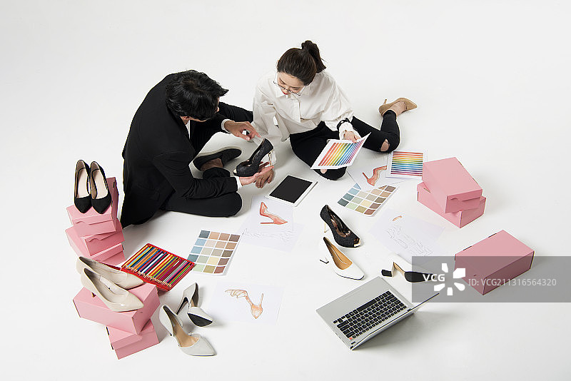 男男女女坐在地板上，旁边是鞋子和盒子，谈论着鞋子的设计图片素材