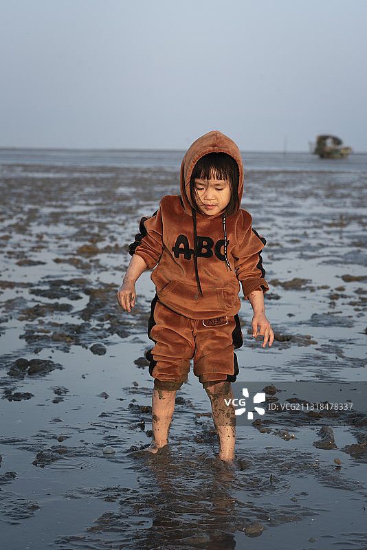 在一望无际的滩涂大海边原始泥泞沙滩上玩耍的小女孩图片素材