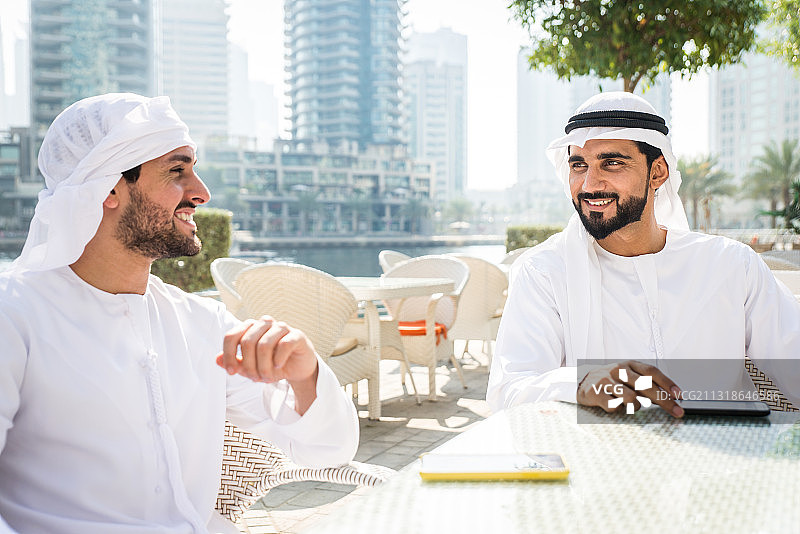 阿拉伯联合酋长国迪拜，两名阿拉伯男子在一个城市里用手机交谈图片素材