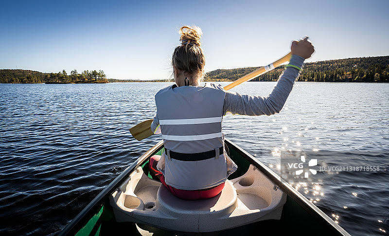 在挪威尼塞德尔湖上划着独木舟的女人的后视图图片素材