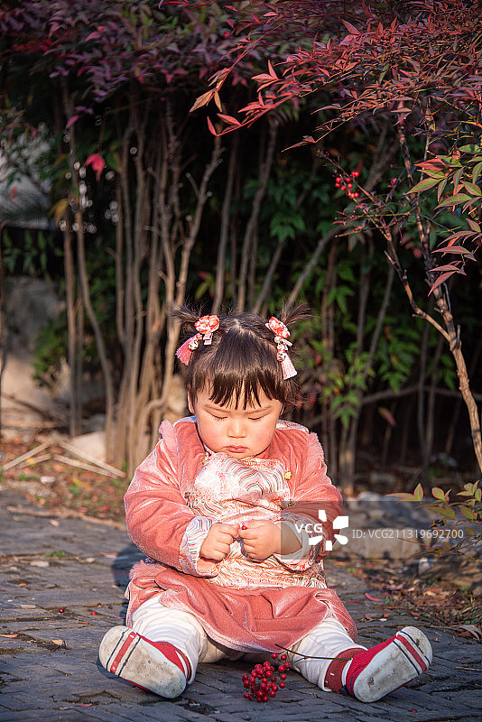 园林里坐在地上玩耍的穿着汉服的小女孩图片素材