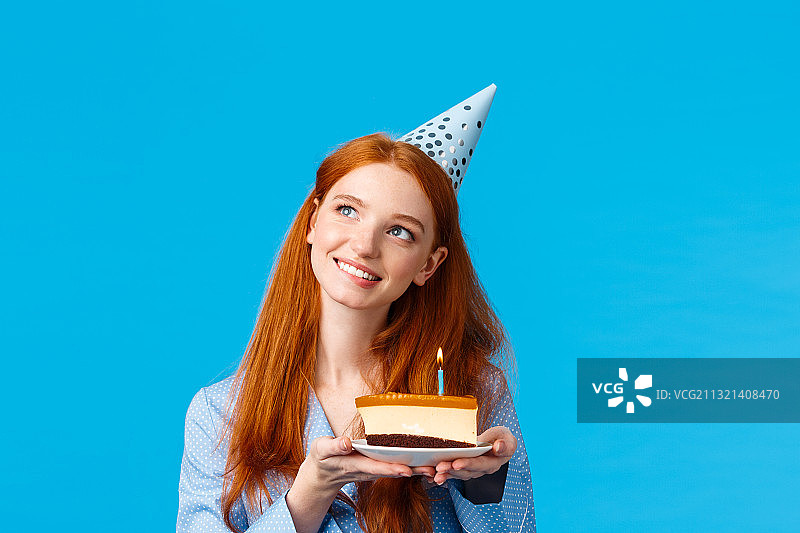 微笑的年轻女子抱着生日蛋糕对蓝色的背景图片素材