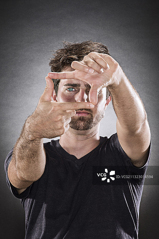 一个男人的肖像，用他的手做一个框架的手势。图片素材