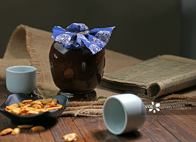 复古酒瓶和酒杯花生米放在木桌上图片素材