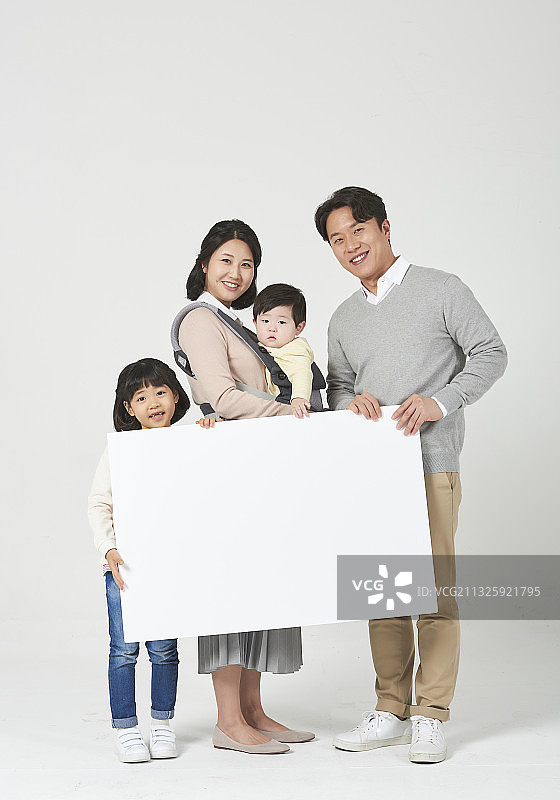 一家人举着白色背景上的白色空白横幅，母亲拥抱着男婴图片素材