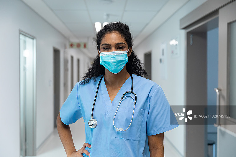 戴着口罩的混血女医生站在医院走廊上的肖像图片素材