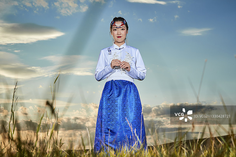 草原上穿着蒙古族传统服饰的亚洲年轻女性图片素材
