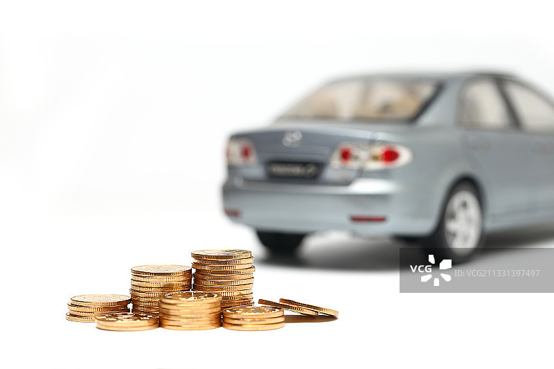 金色硬币放在汽车模型白色背景前图片素材