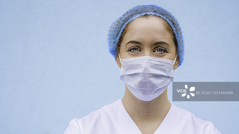 女医生的肖像戴着外科口罩靠墙图片素材