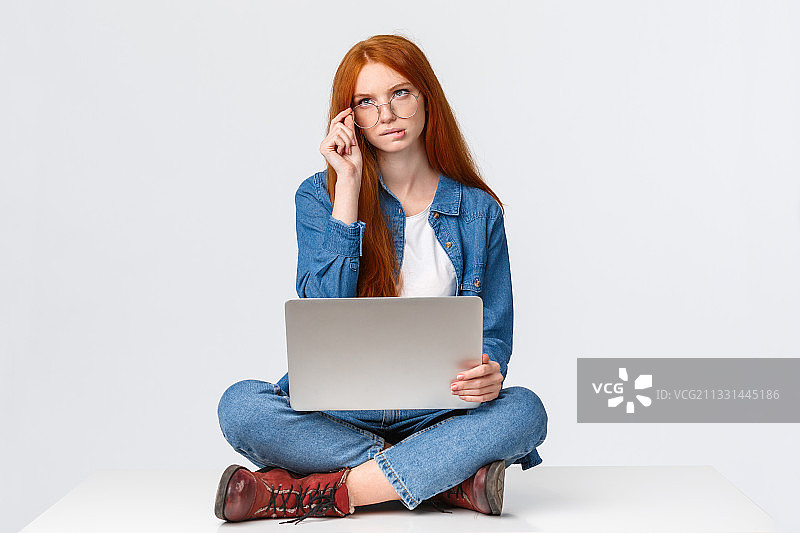 年轻女子坐在白色背景下使用笔记本电脑图片素材