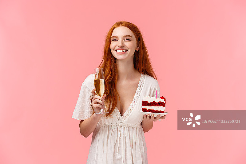 一个微笑的年轻女子在粉红色的背景下拿着冰淇淋的肖像图片素材