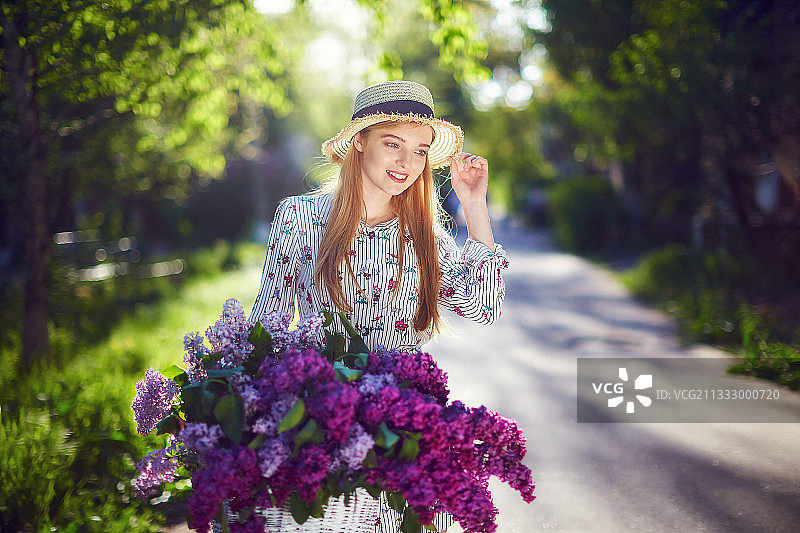 美丽的女人享受着夏日的鲜花在她的自行车上图片素材