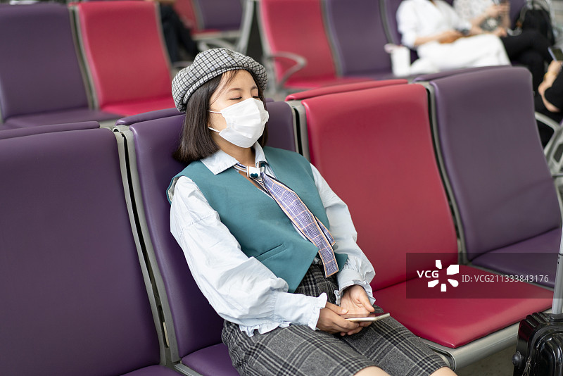 戴着口罩在机场候机的旅游者图片素材