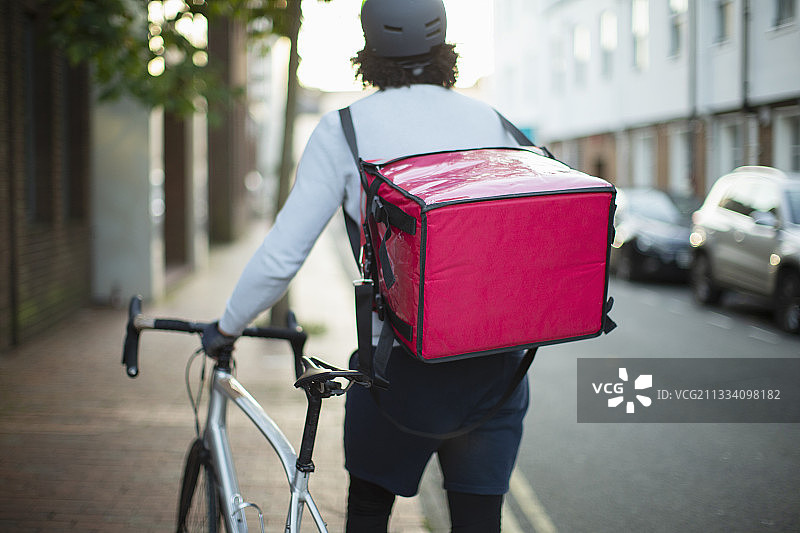 男性自行车信使在城市人行道上送食物图片素材