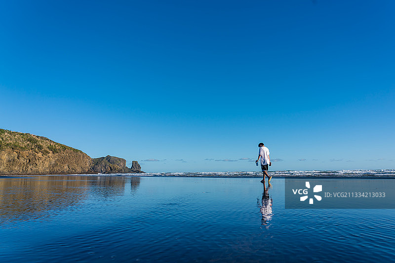在蔚蓝的天空下，一个人站在海滩上图片素材