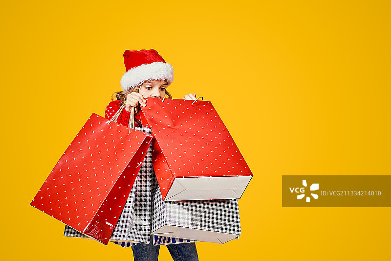 可爱的孩子戴着红色的圣诞帽和毛衣，鹿拿着礼物袋图片素材