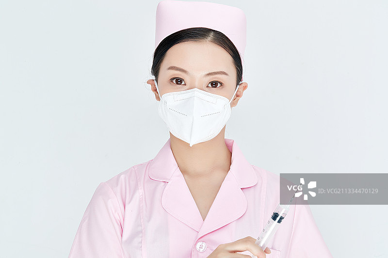穿护士服戴口罩手执针筒的年轻女护士图片素材