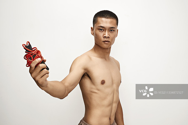 白色背景下手持运动跳绳的亚洲健身男士形象图片素材