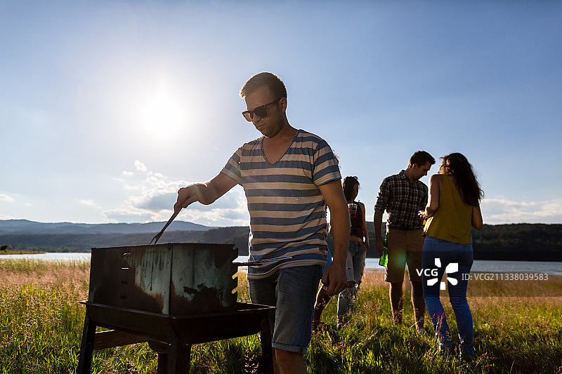 年轻人夏天在河边的野外烧烤图片素材