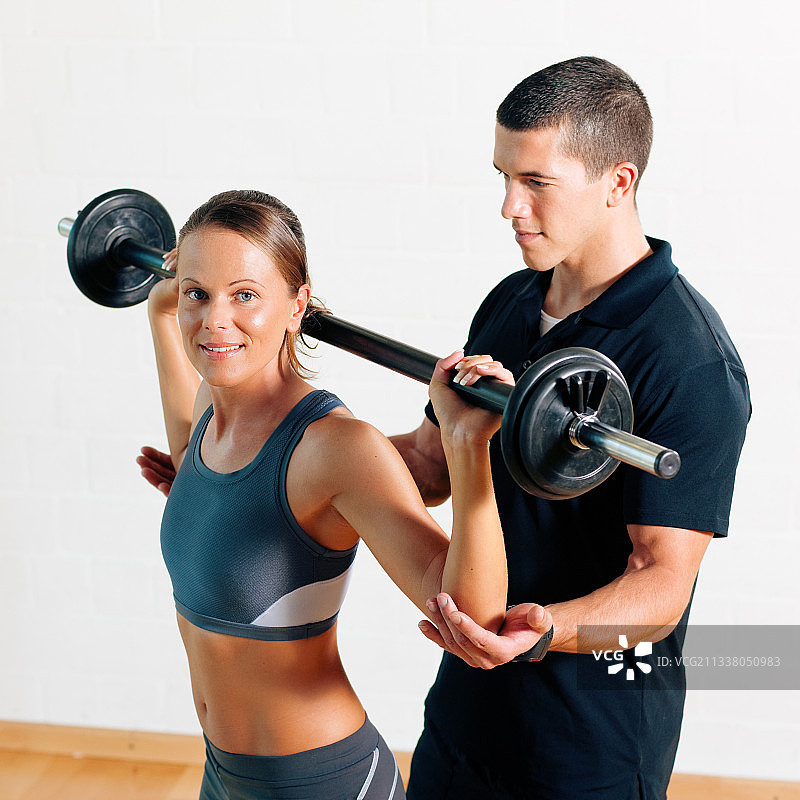 女人和她的私人健身教练在健身房锻炼力量体操与杠铃图片素材