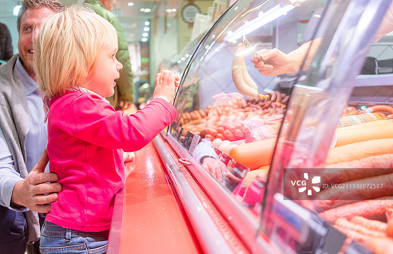 小孩在超市的肉柜台前看一些香肠图片素材