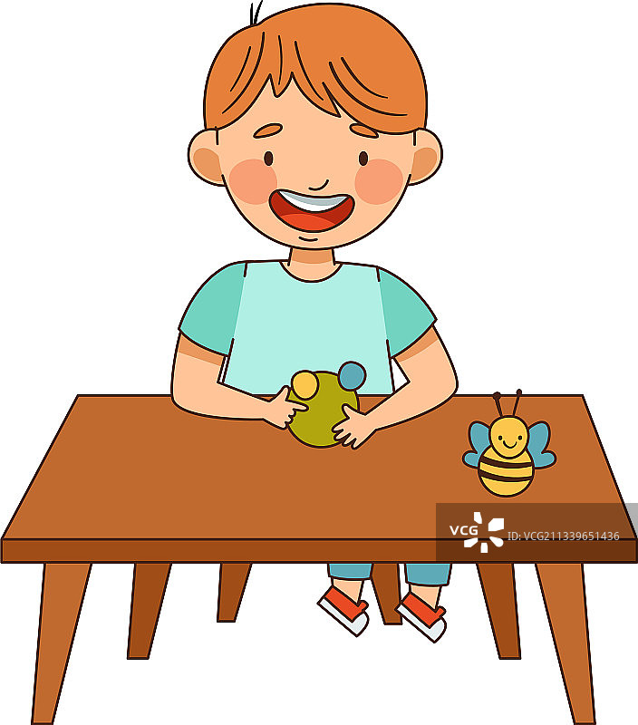微笑的男孩在幼儿园坐在书桌上图片素材