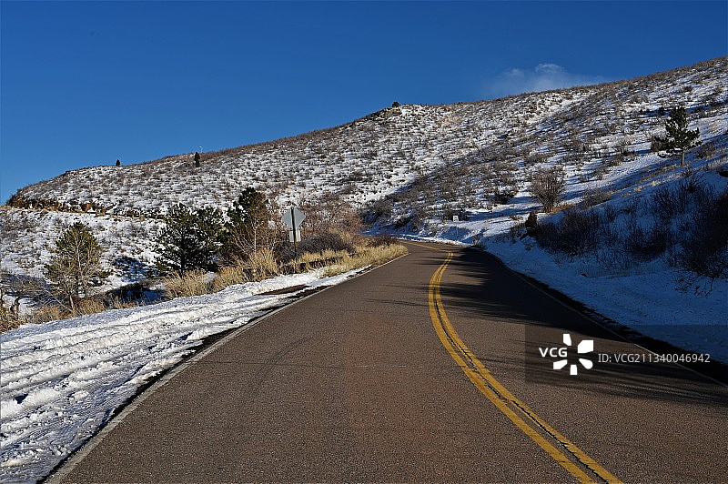 美国科罗拉多州丹佛市，白雪皑皑的群山中空荡的道路，湛蓝的天空图片素材
