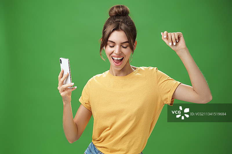 微笑的年轻女子在绿色背景下使用手机图片素材