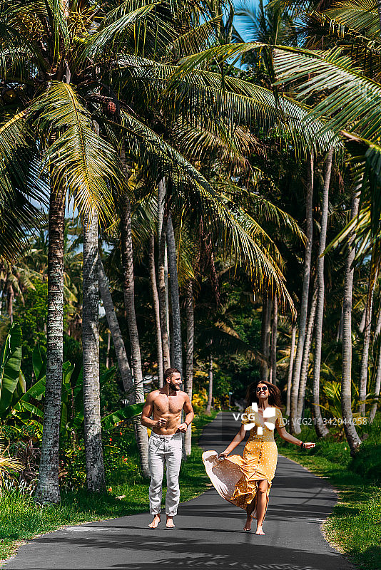 年轻夫妇沿着棕榈树散步图片素材