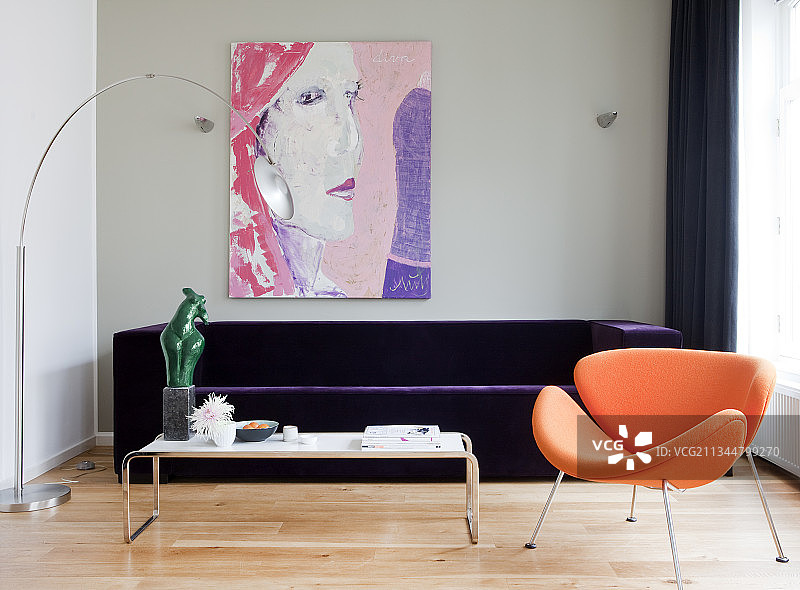 客厅里的紫色天鹅绒沙发前面是橙色的设计师扶手椅图片素材