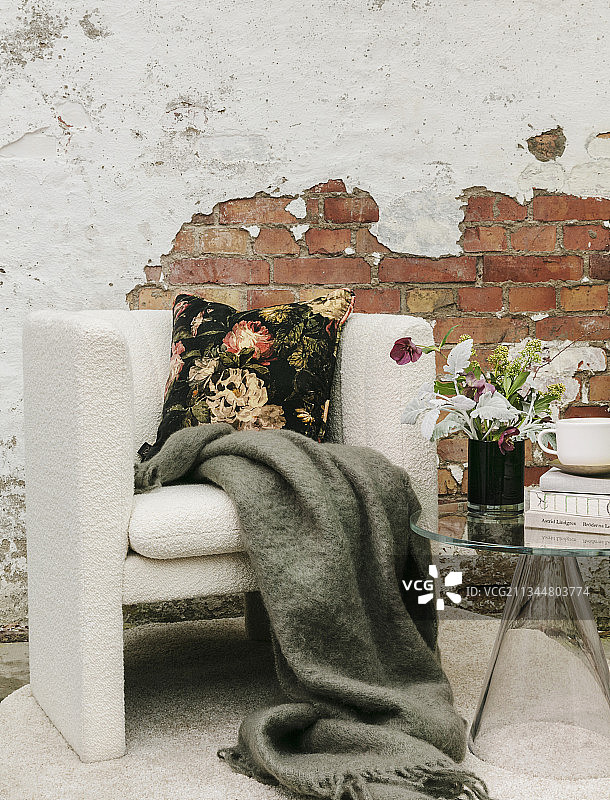 靠砖墙的扶手椅上有毛毯和花卉坐垫图片素材